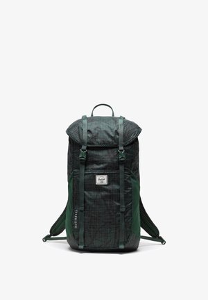 Batoh s tmavo zeleným a čiernym kockovaným vzorom, s nastaviteľnými popruhmi, rolovacím uzáverom a logom na prednej strane.