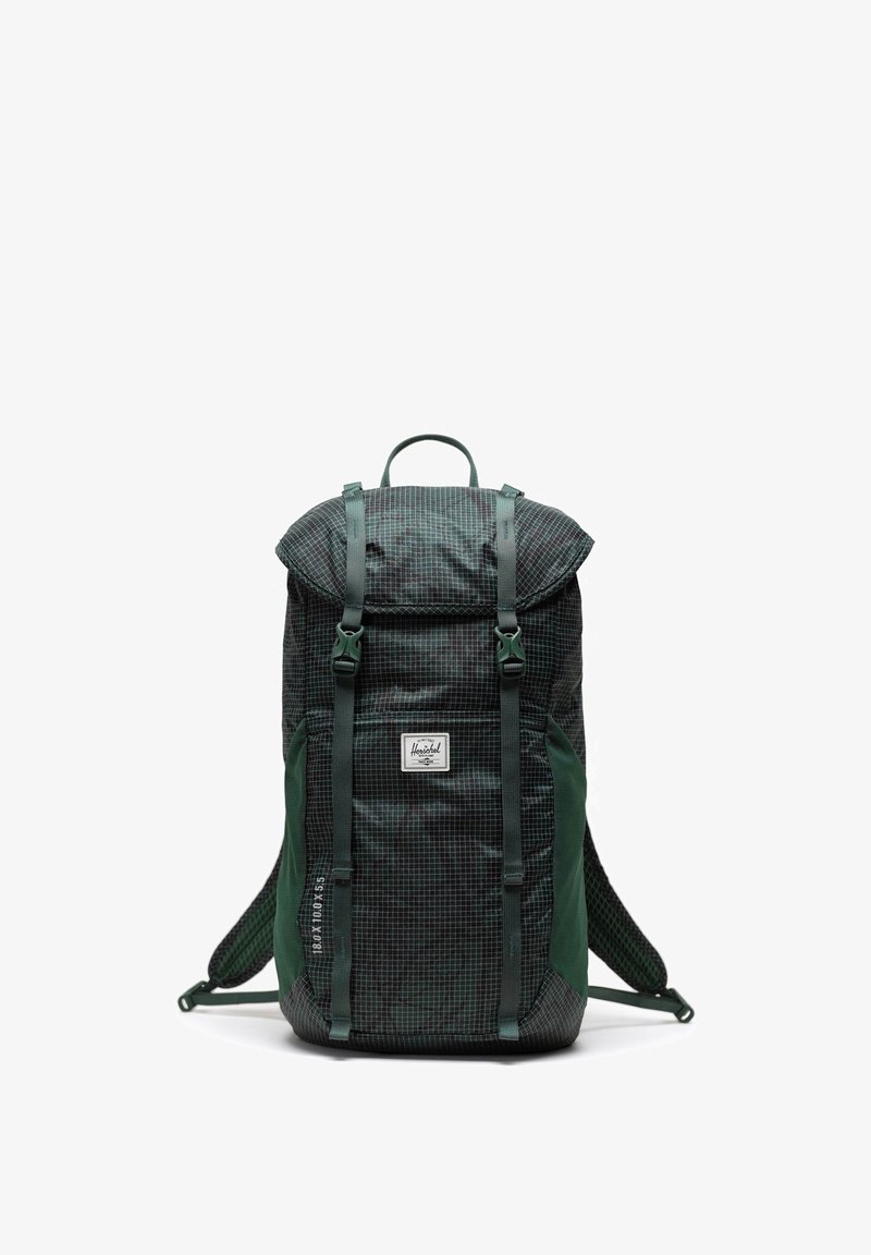 Reppu tummanvihreällä ja mustalla ruudullisella kuviolla, jossa on säädettävät hihnat, rullasuljenta ja logotunnus etupuolella.