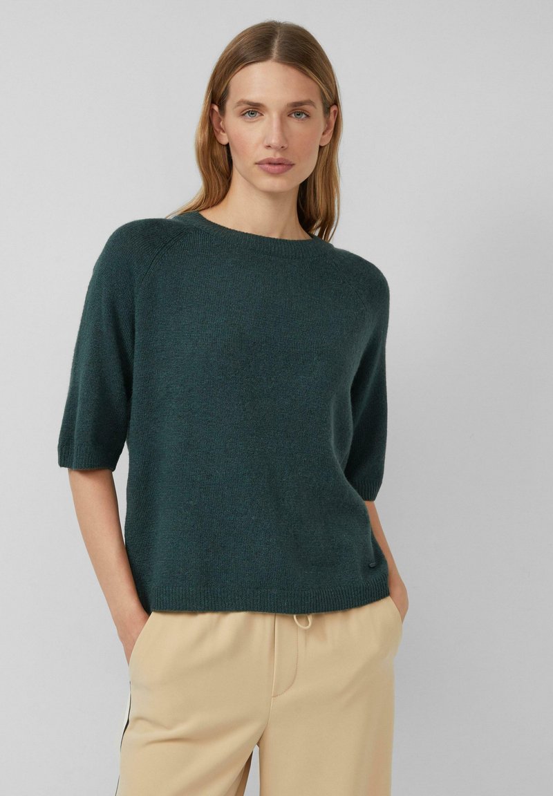 Dunkelgrüner, gestrickter Pullover mit kurzen Ärmeln, rundem Halsausschnitt und entspannter Passform. Weiche Textur mit geripptem Saum und Raglanärmeln.