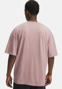Pink cotton t-shirt with a loose fit, short sleeves, and a round neckline. Smooth texture with a simple design. Visible stitching details.