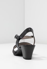 Svart klacksandaler har en slät läderfinish, justerbar ankelrem och en avsmalnande kilklack. Texturerat ovandel och mjukt foder.
