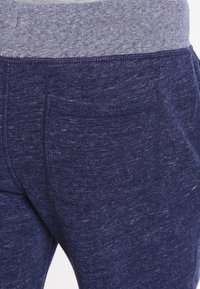 Marineblaue Jogginghosen aus strukturiertem Stoff mit einem melierten Bund und einer Gesäßtasche zur Funktionalität.