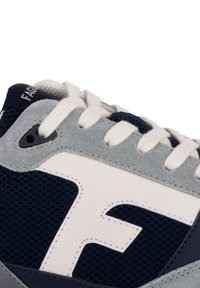 Marineblaue und graue Sneaker aus Mesh, Wildleder und Leder. Mit weißen Akzenten und einem auffälligen Logo an der Seite.