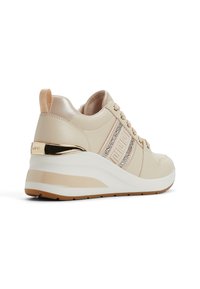 Beige leren sneakers met een sleehak, voorzien van sprankelende accenten en veters, een gladde textuur en een gouden logo detail aan de achterkant.