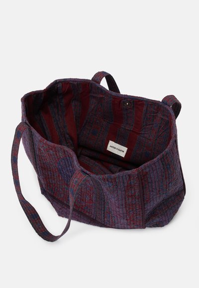 Textilná taška v tmavej fialovej a vínovej farbe s prešívanou štruktúrou; podšívka interiéru s pruhovaným vzorom a značkovou etiketou.