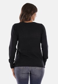 Maglione nero a maglia con maniche lunghe, scollo rotondo e orlo a coste. Tessuto liscio, stile aderente, design minimalista senza motivi.
