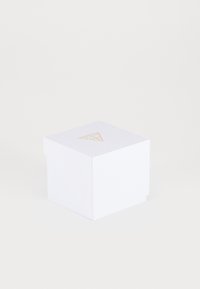 Caja cuadrada blanca con una superficie texturizada, presentando un logo de triángulo dorado en la tapa. Diseño simple, en orientación cerrada.