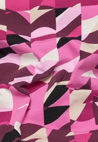 Multicolored fabric featuring a geometric pattern in shades of pink, black, and cream, with a textured surface and soft stretch.