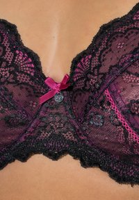 Zwarte kanten bh met een roze satijnen strikje in het midden, bloemenpatronen en geschulpte randen, met een klein metalen detail bij het strikje.