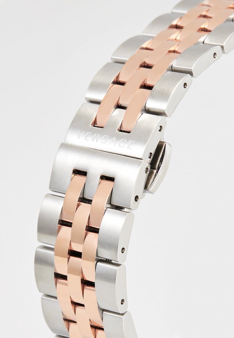 Pulsera de metal en plata y oro rosa con eslabones entrelazados, acabado pulido y grabado de Versace en el cierre.