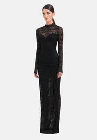 Zwarte kanten avondjurk met lange mouwen, hoge halslijn, aansluitend lijfje en geplooide zijdetails. Doorschijnende stof met bloemenpatroon en gespleten rok.