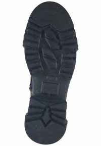Suela de zapato de goma negra con surcos profundos; presenta patrones en zigzag y superficie texturizada para mayor tracción; tacón redondeado y bordes reforzados.