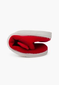 Pantofola rossa in tela, design pieghevole, suola in gomma bianca, interno morbido con cinturino in velcro per una vestibilità sicura. La parte superiore testurizzata completa la flessibilità.