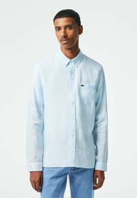 Camicia a maniche lunghe azzurro chiaro, realizzata in un tessuto morbido, con colletto button-down, tasca frontale e piccolo logo sul petto.