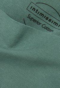Groene katoenen stof met een gestructureerde afwerking. Bevat een label met de tekst "intimissimi Superior Cotton," dat het merk en de materiaalkwaliteit aangeeft.