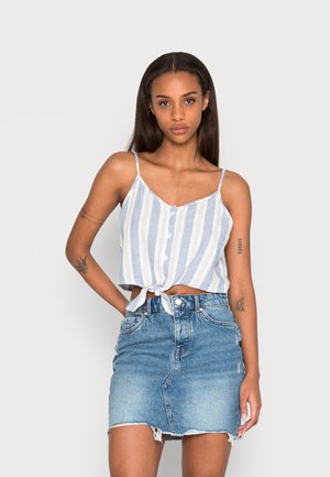 Top cropped listrado azul e branco com detalhe de nó na frente, combinado com uma saia mini de denim de cintura alta com bainha desfiada.