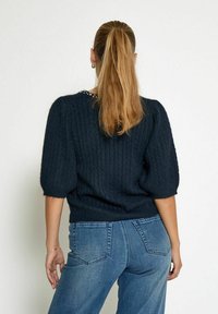 Navy blue knitted sweater with ribbed texture, short puff sleeves, and a rounded neckline featuring a pearl accent along the back.