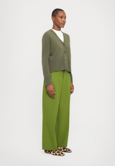 Olive green cropped cardigan with a V-neck and button closure, paired with high-waisted, wide-leg green trousers and leopard-print shoes.