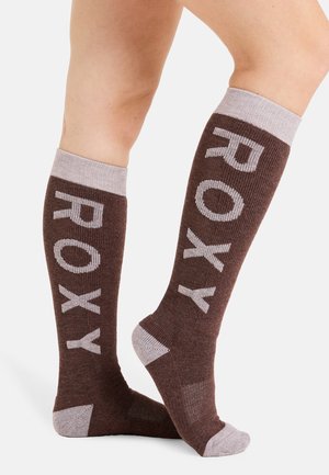 Braune knielange Socken mit hellgrauer "ROXY"-Beschriftung. Sie verfügen über eine gerippte Textur und kontrastierende hellgraue Akzente an Bündchen und Ferse.