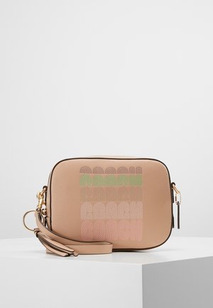 Tan-nahkainen rannepussi, jossa kullanväriset metalliosat, pastellivärinen "Coach"-logokuvio ja irrotettava olkahihna valkoisella esittelyalustalla.