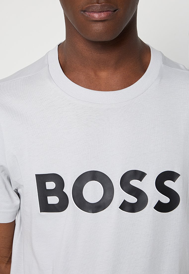 Camiseta de algodón blanca con un destacado logotipo negro "BOSS" en fuente negrita. Textura suave con cuello redondo y mangas cortas.