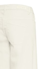 Jean en denim blanc montrant la poche arrière et l'étiquette de la ceinture avec la marque "ICHI", présenté sur un fond blanc uni.