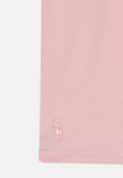 Camiseta de algodón rosa con un pequeño logo bordado en un tono ligeramente más oscuro en la esquina inferior izquierda. Textura suave, diseño sencillo.