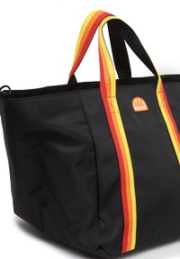 Borsa tote in tessuto nero con manici a strisce rosse, gialle e arancioni. Presenta un logo circolare su un lato e un ampio scomparto aperto.