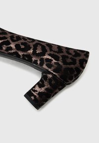Black and bronze leopard print high-heel shoe with a round toe and a chunky heel, featuring a textured suede-like material.