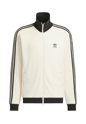 Veste de survêtement Adidas blanche avec col, poignets et ourlet noirs, trois bandes noires le long des manches, fermeture éclair frontale et logo Adidas sur la poitrine.