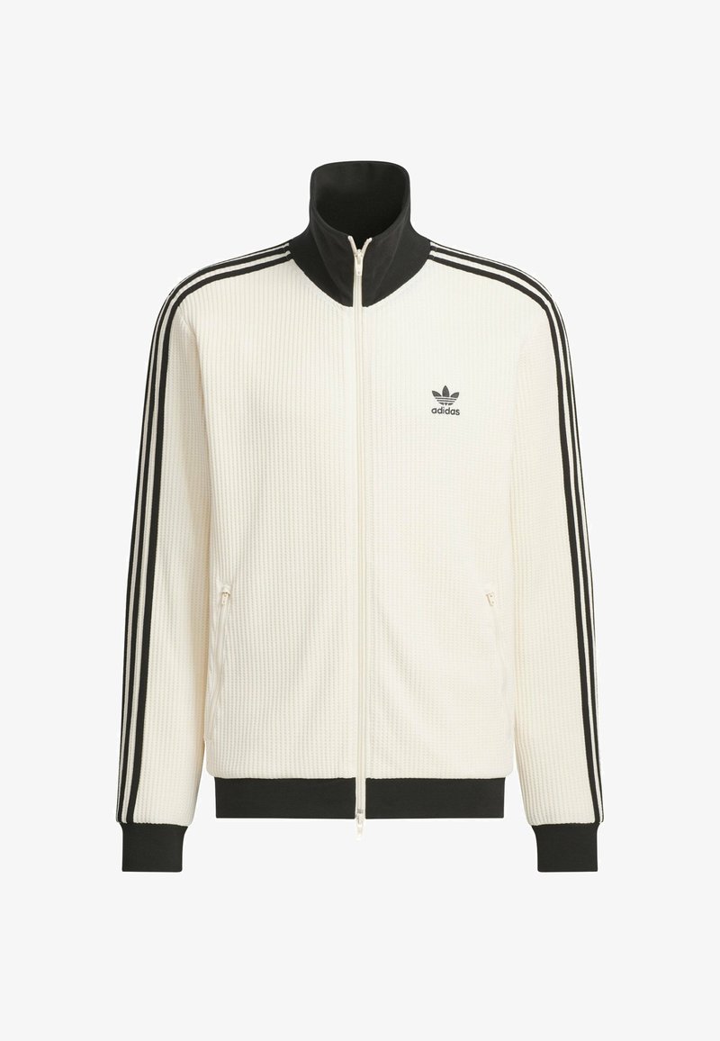 Hvid Adidas-træningsjakke med sort krave, manchetter og kant, tre sorte striber ned ad ærmerne, lynlås foran og Adidas-logo på brystet.