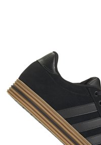 Sneakers in camoscio nero con dettagli in pelle nera, caratterizzati da tre strisce orizzontali, un tallone testurizzato e una suola in gomma naturale.