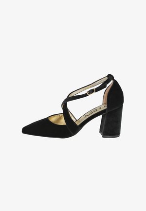 Zapato de tacón alto de terciopelo negro con punta afilada, correas en el tobillo y un tacón grueso de bloque. Forro interior dorado y detalle de diseño con correas cruzadas.