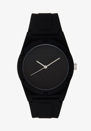 Montre-bracelet noire avec bracelet en silicone, cadran rond affichant un logo triangulaire en relief discret et des aiguilles d’heure, de minute et de seconde argentées.