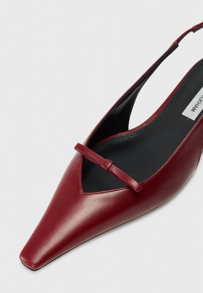Burgundská kožená slingback obuv s ostrou špičkou, s výrezom a štíhlym remienkom. Hladký povrch s čiernou stielkou.