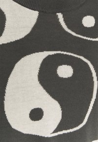 Tissu en maille noire avec de grands symboles yin-yang blancs contrastants, à la texture lisse et aux détails tissés subtils.