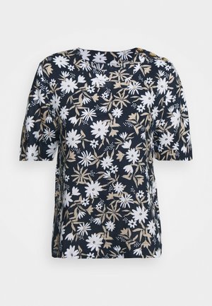 Chemise bleu marine à manches courtes avec motif floral blanc et beige et deux boutons dorés sur l'épaule gauche.