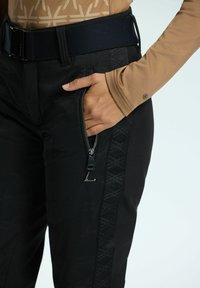 Zwarte broek met een textuurgedeelte aan de zijkant, voorzien van een ritszak. De tailleband is elastisch en de stof heeft een subtiel patroon.