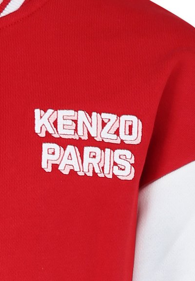 Sweatshirt en coton rouge avec des accents blancs, comportant un texte brodé "KENZO PARIS" en typographie en gras sur la poitrine gauche.