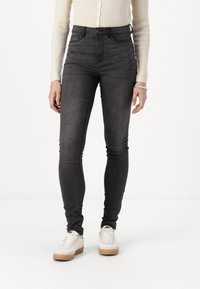Høyt midje, smale jeans i mørkegrå denim. Har en jevn tekstur, knappelukking og minimale sømdetaljer på lommene.