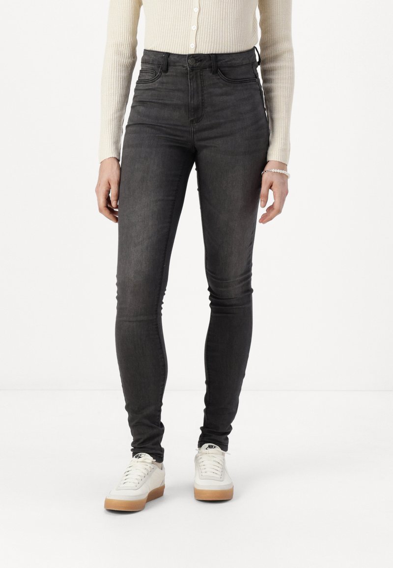 Høyt midje, smale jeans i mørkegrå denim. Har en jevn tekstur, knappelukking og minimale sømdetaljer på lommene.