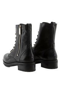 Schwarze Leder-Stiefeletten mit einem seitlichen Reißverschluss, Schnürung vorne und einem dicken Absatz. Mit einem kleinen Logo nahe dem Absatz. Glatte Textur.