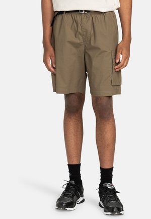 Khaki cargo shorts with an elastic waistband, side pocket, and lightweight fabric. Worn with black athletic shoes and socks.