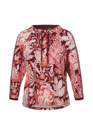 Bloemrijke tuniek in diep bordeauxrood met roze en witte botanische patronen. Heeft een ronde halslijn en driekwart mouwen. Zachte stofuitstraling.