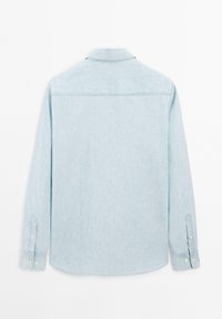 Camicia azzurra a maniche lunghe con bottoni e colletto, vista da dietro, con polsini abbottonati e dettaglio sullo yoke.