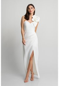 Biała, asymetryczna sukienka na jedno ramię z falbaną, dopasowanym gorsetem i rozcięciem do uda. Gładka tkanina i elegancka, wydłużona sylwetka.