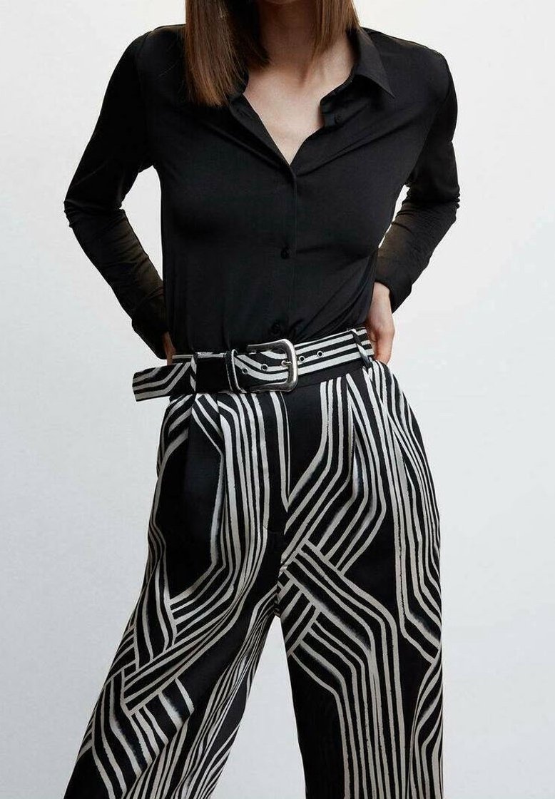 Black long-sleeve button-up shirt paired with high-waisted black and white striped wide-leg pants featuring a belt and bold geometric pattern.