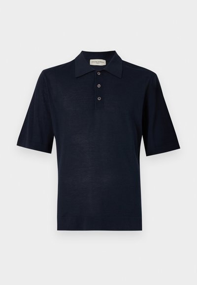 Tumesinine polo särk, mis on valmistatud pehmest kangast, klassikalise kraega, kolme nööbiga keskosa ja lühikeste varrukatega. Sile tekstuur, minimaalne disain.