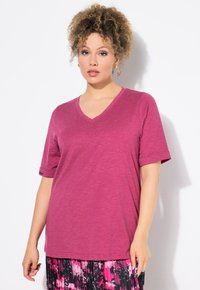 V-hals korte mouwen T-shirt in gemeleerd magenta stof, met eenRelaxed fit en opgerolde mouwen. Gecombineerd met een patroon van zwart en roze onderstuk.