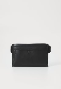 Borsa a tracolla nera in pelle con finitura testurizzata, chiusura con zip, tracolla regolabile e logo Calvin Klein impresso sul davanti.